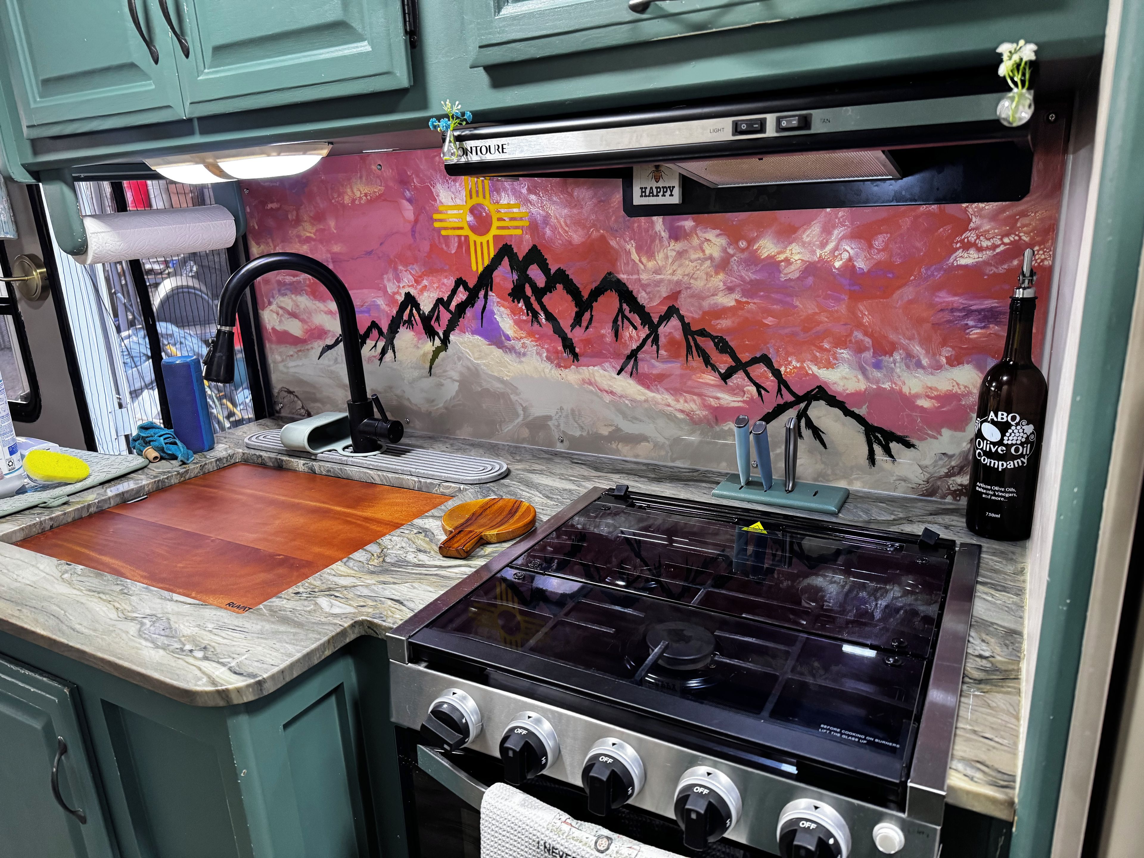 Una cocina con estufa a gas, un lavamanos y una encimera con varios objetos.