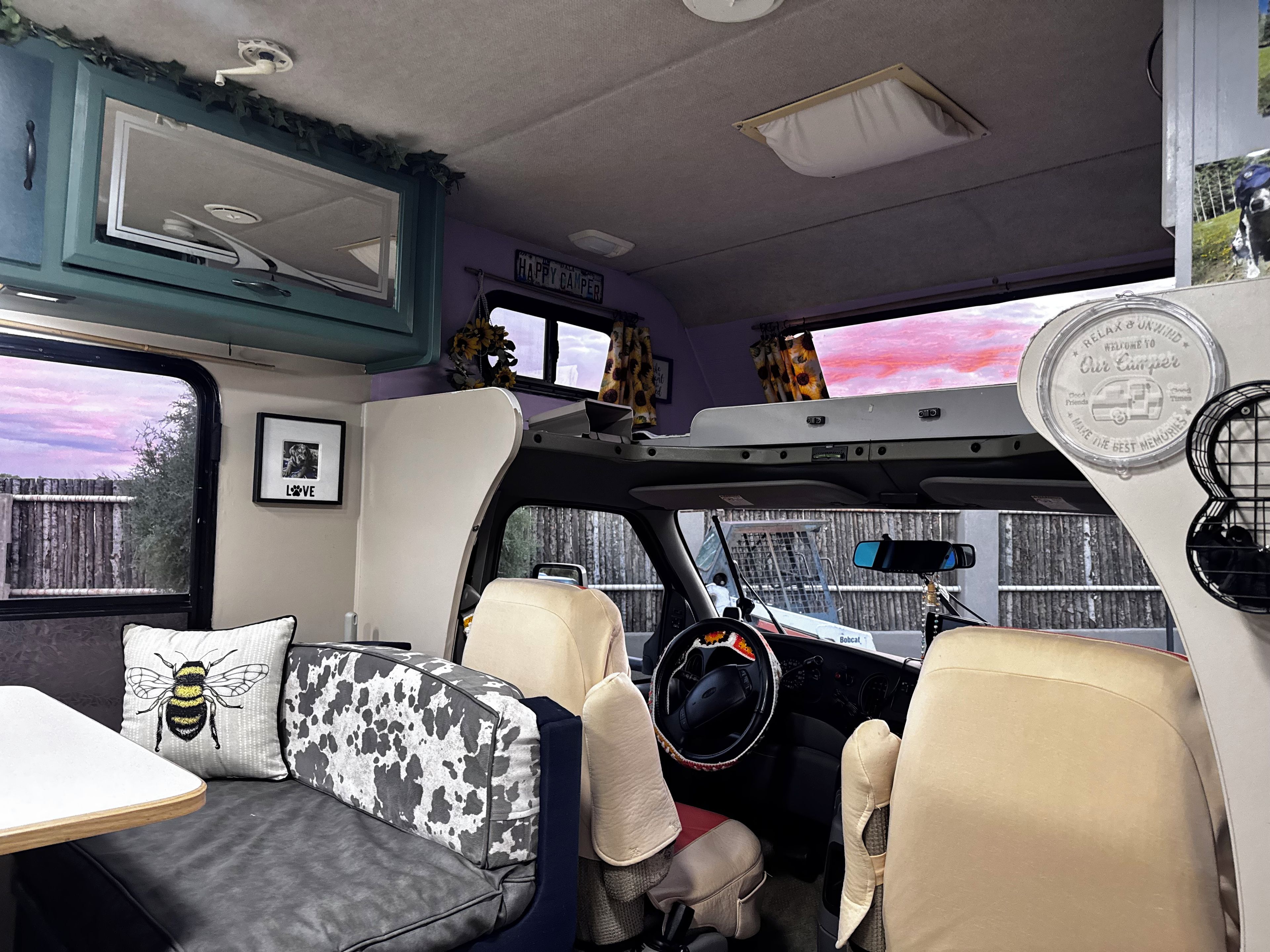 Interior de campervan con cama, zona de estar y volante.