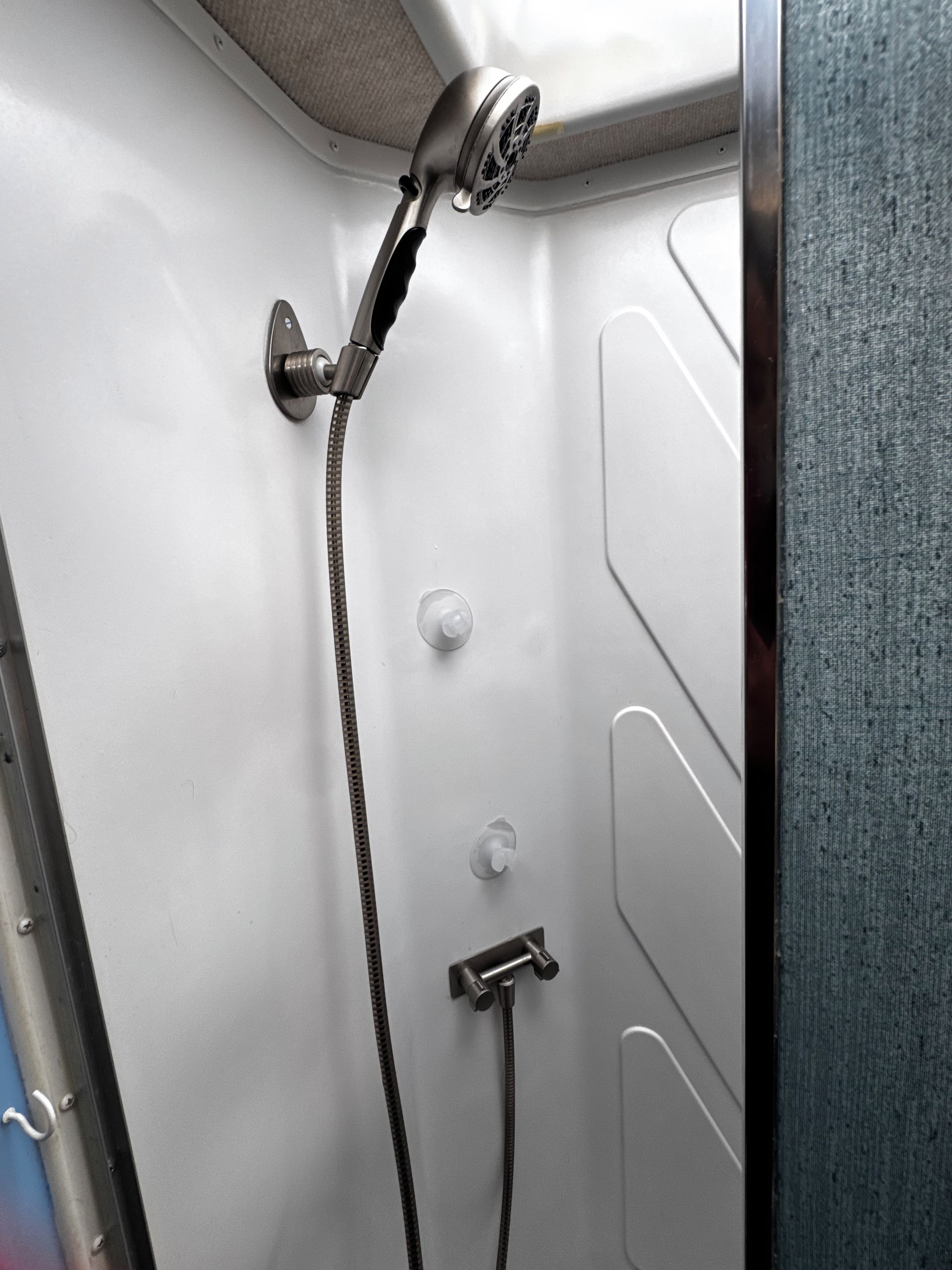 A shower with a handheld showerhead and a handheld hose.