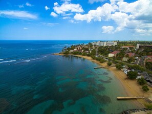 A coastal town with a beach, clear blue waters, and buildings along the shore. - Dorado Cove | Modern Pool & Beach Escape (Dorado)