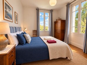 A bedroom with a bed, a nightstand, a lamp, a dresser, and a window with curtains. - Domaine du Cèdre (L'Aigle)