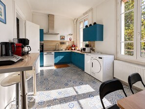 A modern kitchen with a washing machine, a coffee machine, and a microwave. - Domaine du Cèdre (L'Aigle)