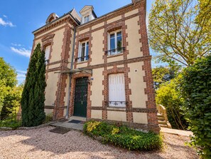 A two-story building with a symmetrical facade, a central entrance with a green door, and a brick pattern. - Domaine du Cèdre (L'Aigle)
