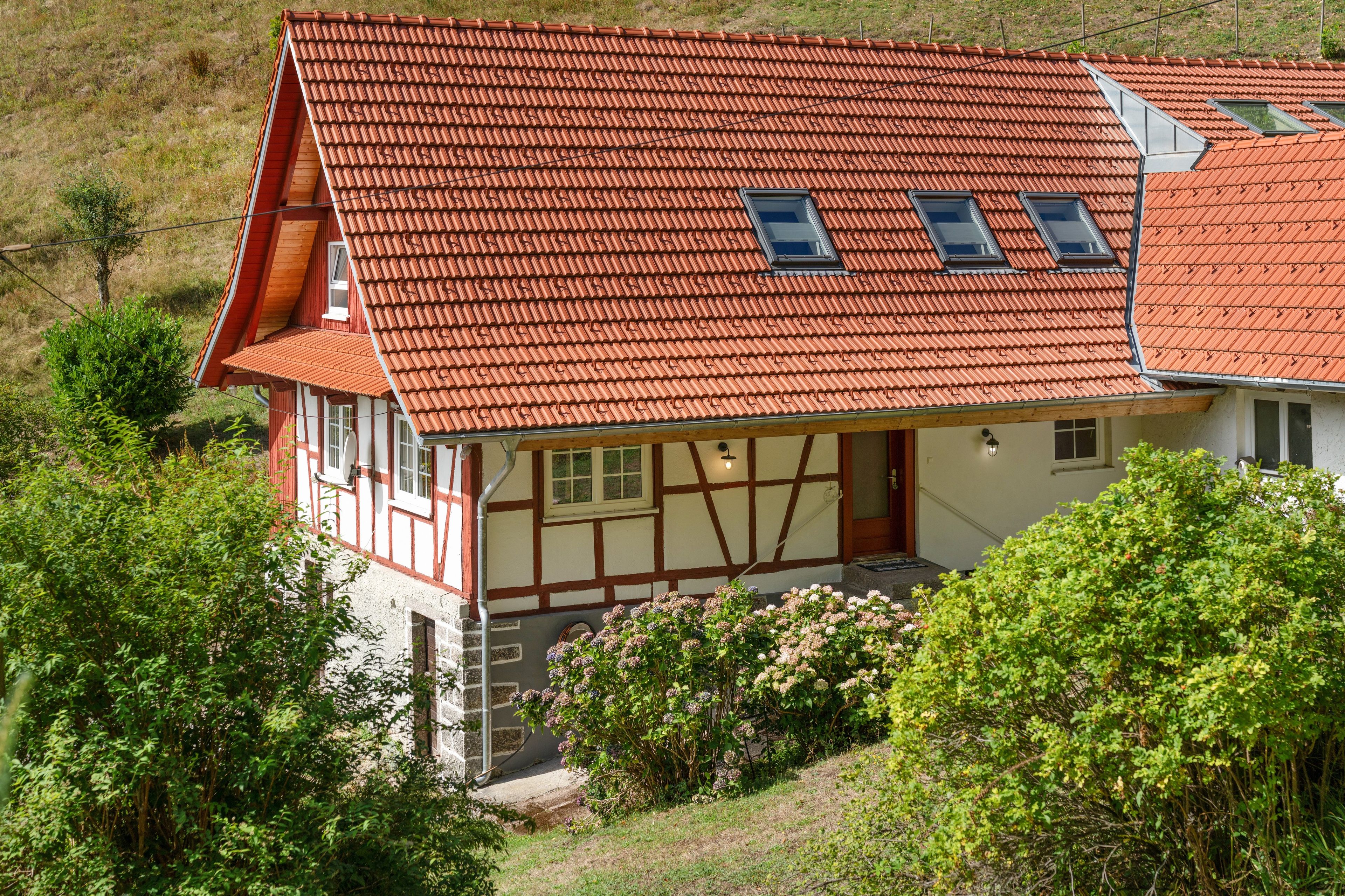 Ein traditionelles Fachwerkhäuschen mit einem geneigten roten Ziegeldach und Dachgauben.