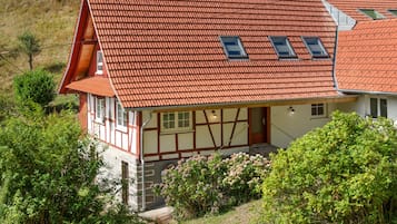 Ein traditionelles Fachwerkhäuschen mit einem geneigten roten Ziegeldach und Dachgauben.