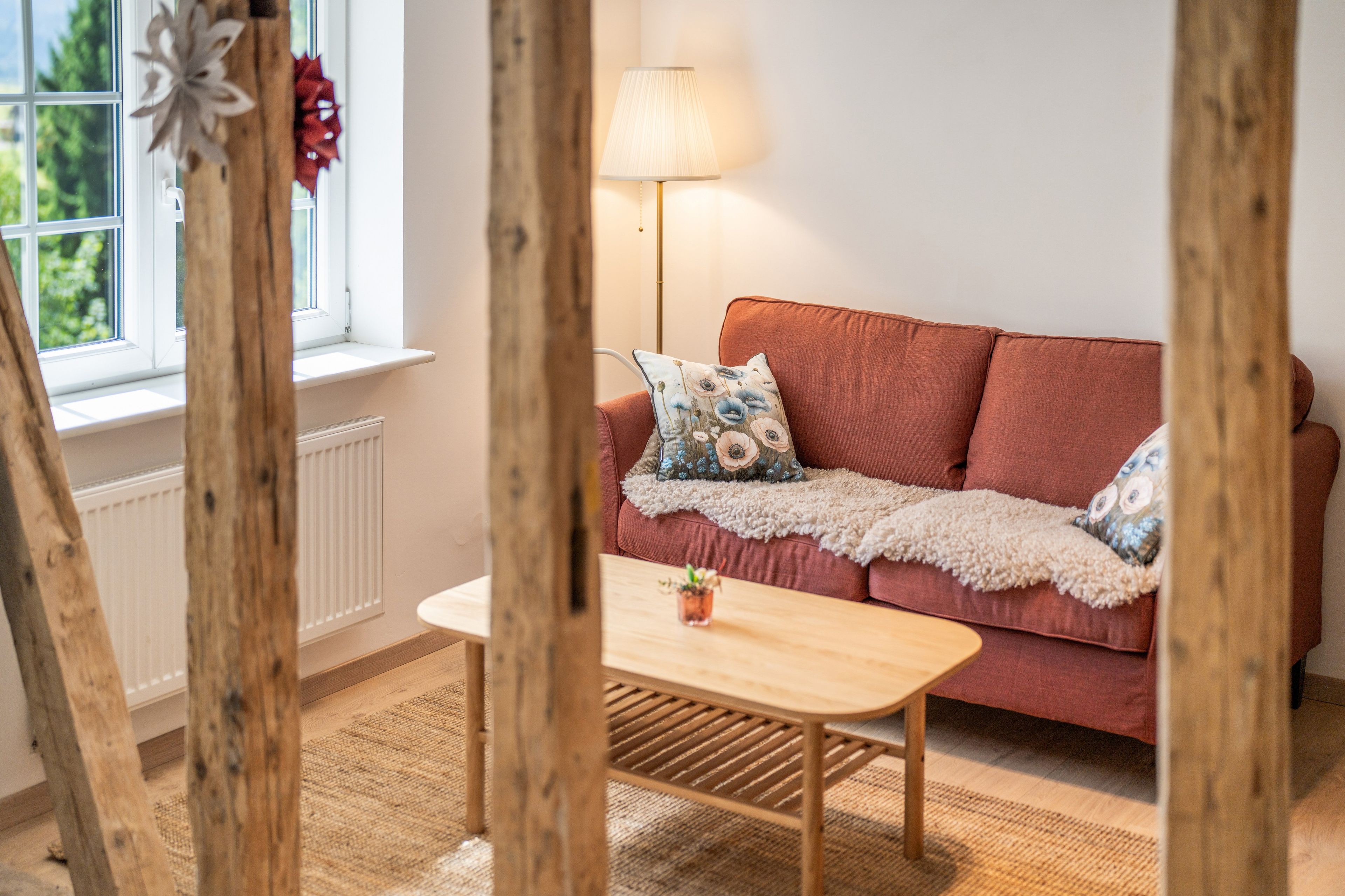 A cozy room with a red sofa, a wooden table, and a lamp.