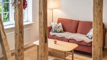 A cozy room with a red sofa, a wooden table, and a lamp.
