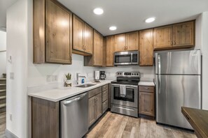 Una cocina moderna con armarios de madera, electrodomésticos de acero inoxidable y una encimera blanca.