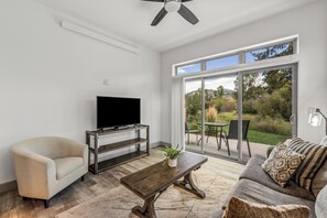 Een moderne woonkamer met een flatscreen televisie, een bank, een salontafel en een schuifdeur naar een terras.