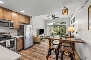 A modern kitchen with stainless steel appliances, wooden cabinets, and a dining area with a bar stool and table. - Charming Riverfront Property Close to the Resort! Pet Friendly! (Steamboat Springs)