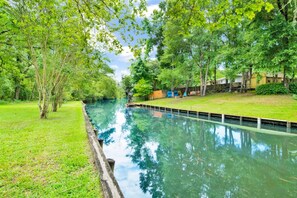 A tranquil waterway flanked by lush greenery and a wooden dock. - Kings Landing (Theodore)