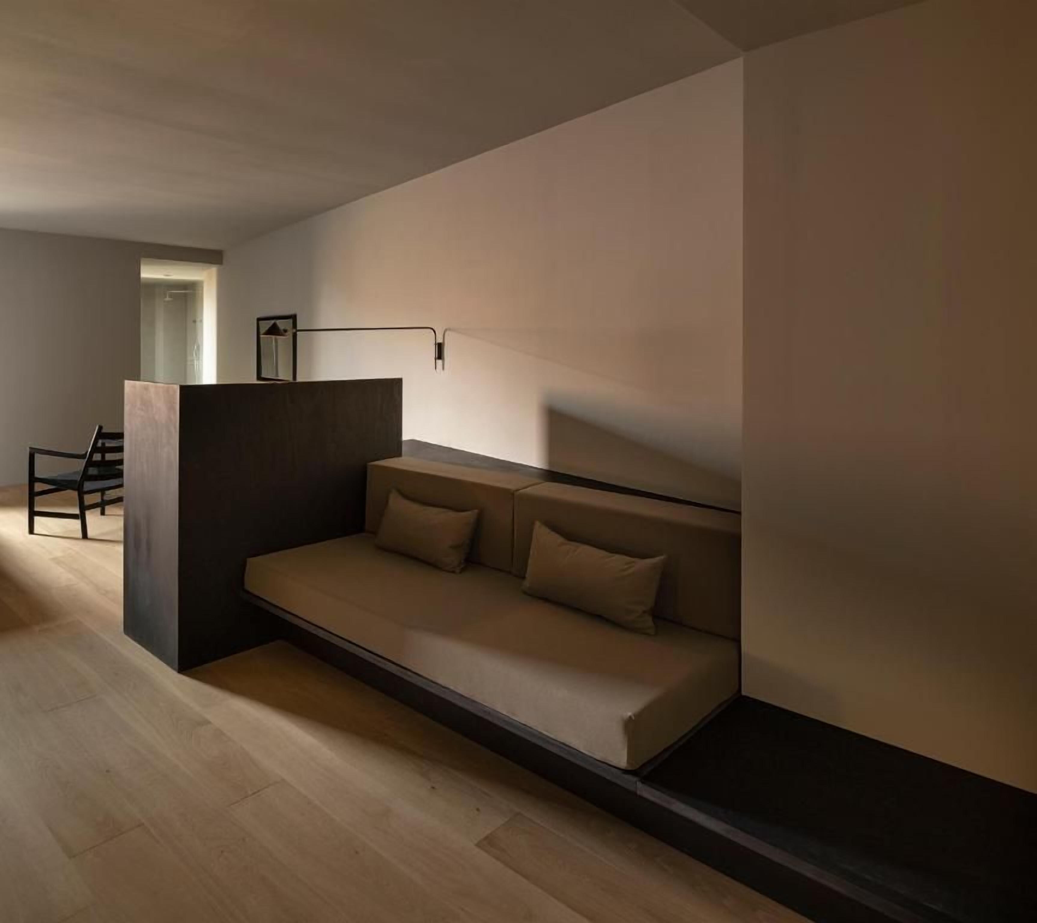 Un salón minimalista con un sofá, una silla y un escritorio.