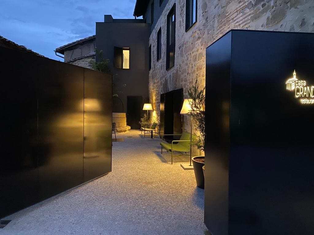 Un patio con zona de estar, un edificio de fachada de piedra y un letrero que dice 'Casa Grand Restaurante'.