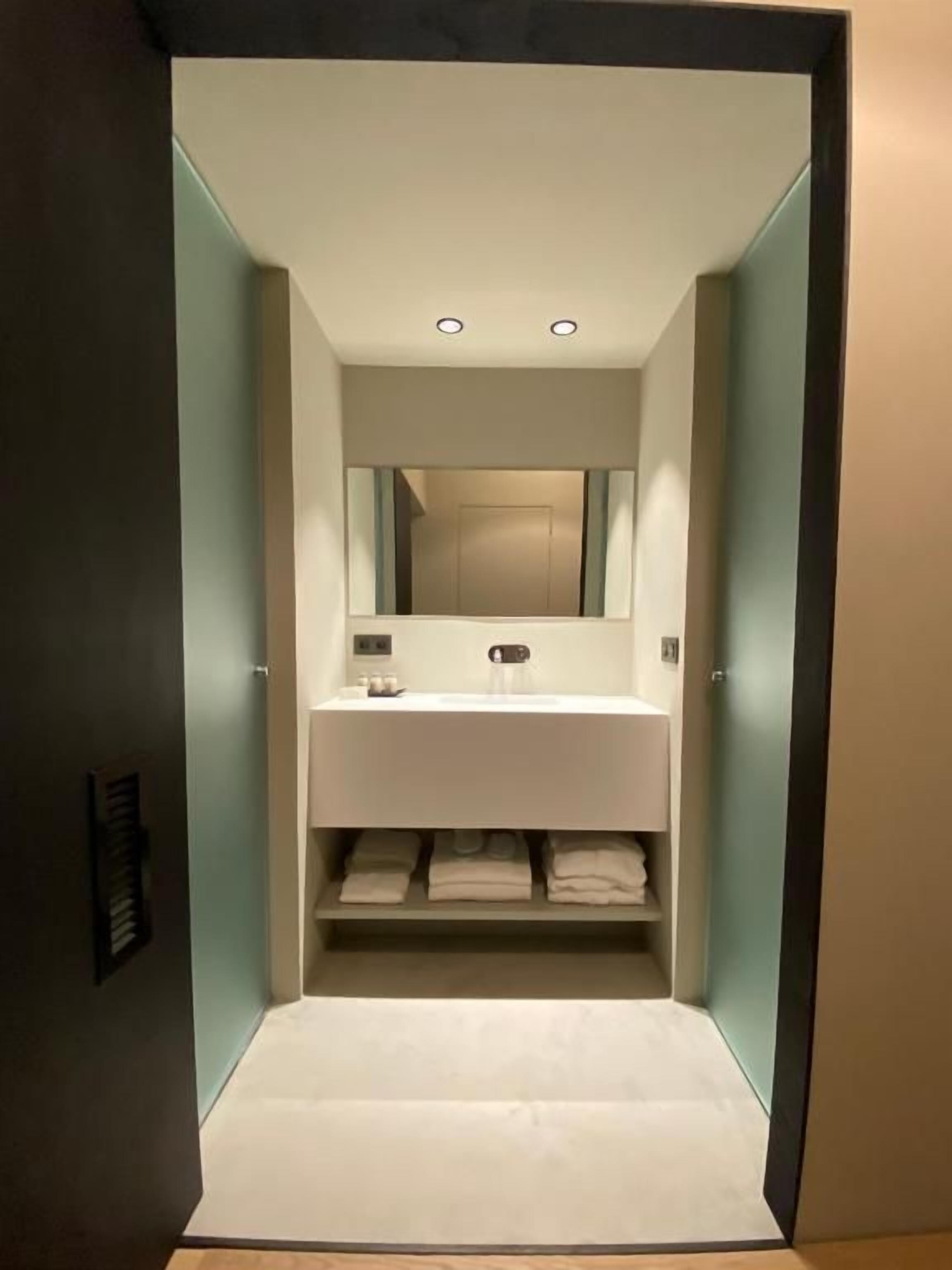 Un baño moderno con tocador blanco, espejo arriba y barra para toallas abajo.
