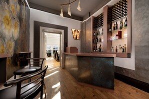 A bar area with a counter, seating, and a wine rack. - Finest Retreats | Westwell Hall (Ilfracombe)
