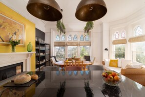 A dining area with a black marble table, wooden chairs, and a bowl of fruit. - Finest Retreats | Westwell Hall (Ilfracombe)