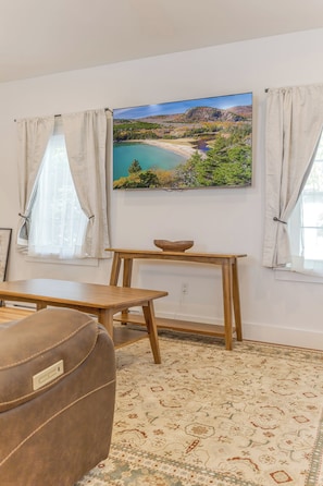 Una habitación con una mesa de madera, un sofá y un cuadro de un paisaje.