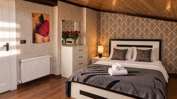 Un dormitorio con cama, mesita de noche, lámpara y cómoda con espejo y flores.