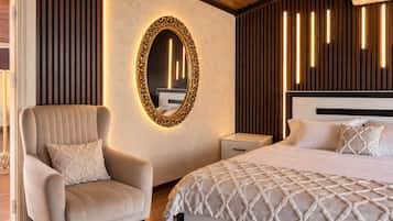 Un dormitorio moderno con una cama grande, un espacio de descanso con una silla, una mesita de noche y un espejo instalado en la pared.
