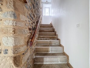 Eine Treppe mit Steinwänden und einem Holzgeländer, die zu einer Tür mit einem Fenster darüber führt.