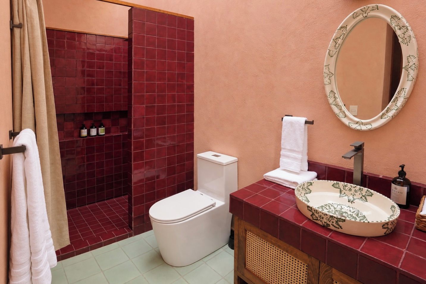 A bathroom with a shower, toilet, sink, and a mirror.