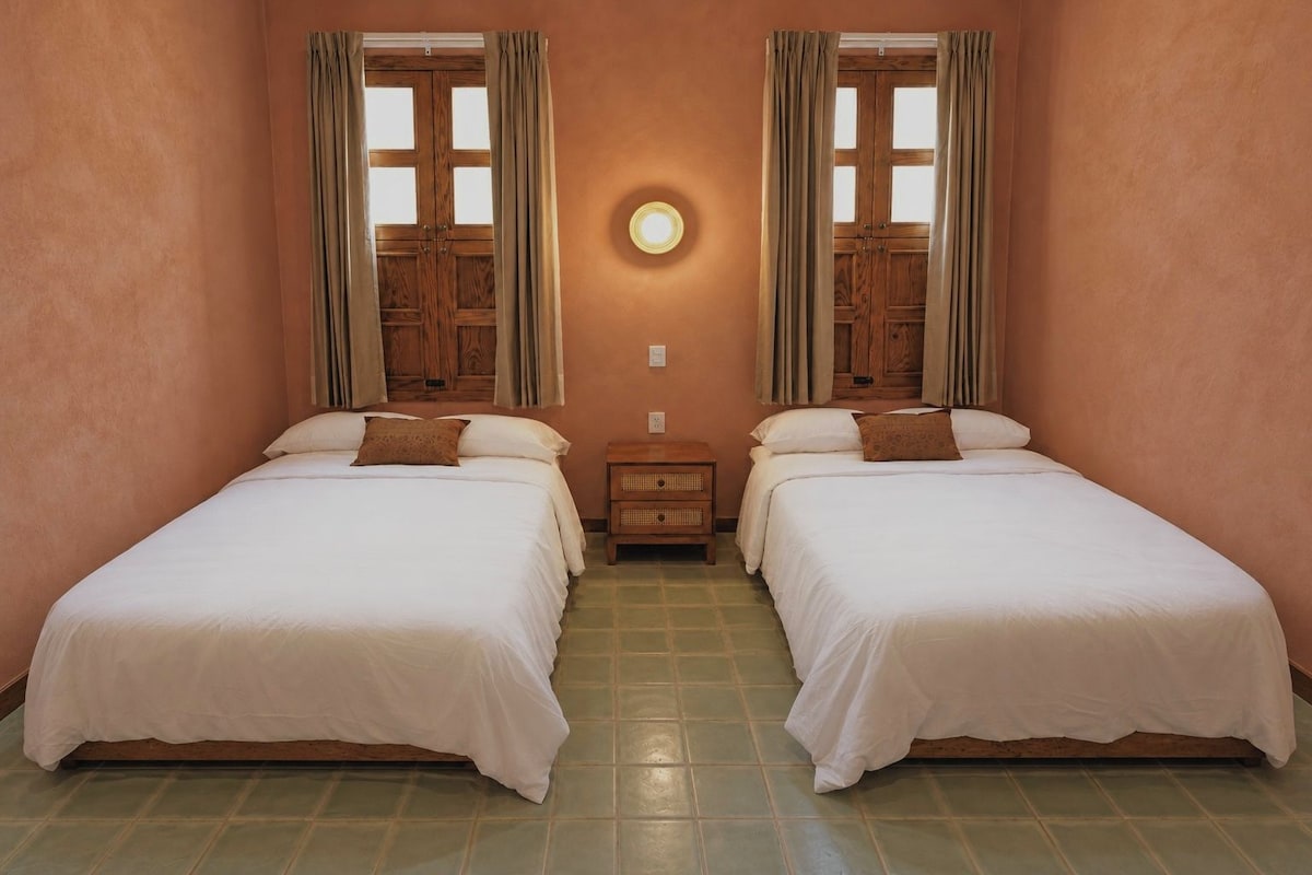 Une chambre avec deux lits, une table de chevet et une horloge murale ronde.