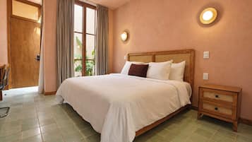 Une chambre à coucher avec un grand lit, une table de chevet et une fenêtre avec des rideaux.