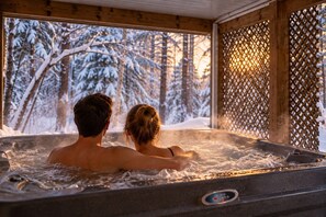 A couple in a hot tub with a view of snow-covered trees. - Le Havre | Private Hot Tub | Hammock & Lake (Mansonville)
