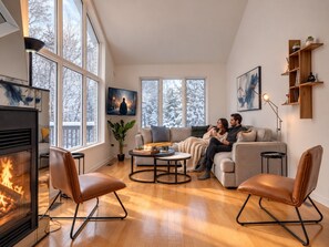 A cozy living room with a fireplace, large windows, and a comfortable seating area. - Le Havre | Private Hot Tub | Hammock & Lake (Mansonville)