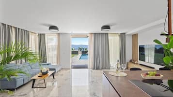 Una sala de estar moderna con un sofá, una mesa de centro y vista a una piscina exterior.
