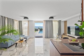 Una sala de estar moderna con un sofá, una mesa de centro y vista a una piscina exterior.