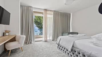 A hotel room with a bed, a desk, a television, and a view of the outdoors.