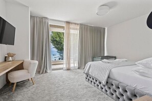 Una habitación de hotel con cama, escritorio, televisión y vista al exterior.