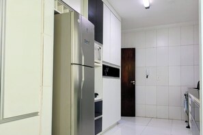 Une cuisine avec des meubles blancs, un réfrigérateur en acier inoxydable et une porte en bois foncé.