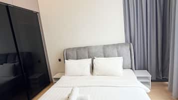 A hotel room with a bed, a nightstand, a wardrobe, and a window with curtains.