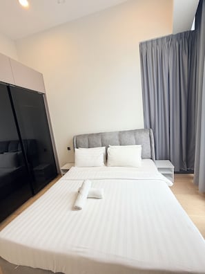 A hotel room with a bed, a nightstand, a wardrobe, and a window with curtains. - Colony Infinitum Sky Pool KLCC (Kuala Lumpur)