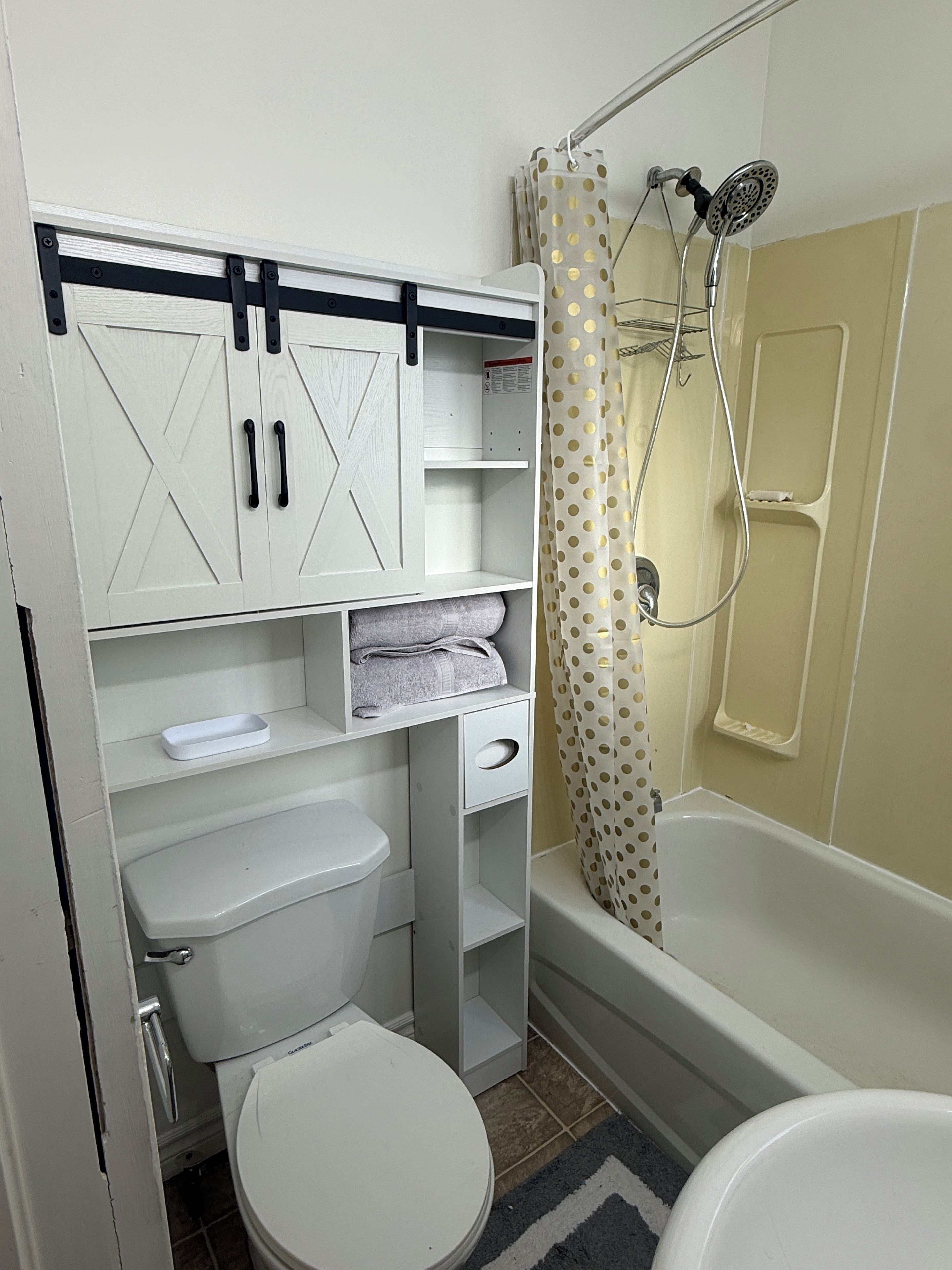 A bathroom with a toilet, a sink, a shower with a curtain, and a cabinet with storage space.