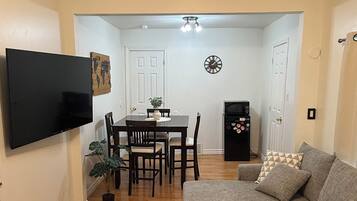 Un salon équipé d’un téléviseur à écran plat, d’un canapé, d’une table basse et d’un coin repas avec des chaises et une table.
