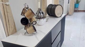 Een moderne keuken met een zwart-wit aanrecht, een kom met keukengerei en een potplant.
