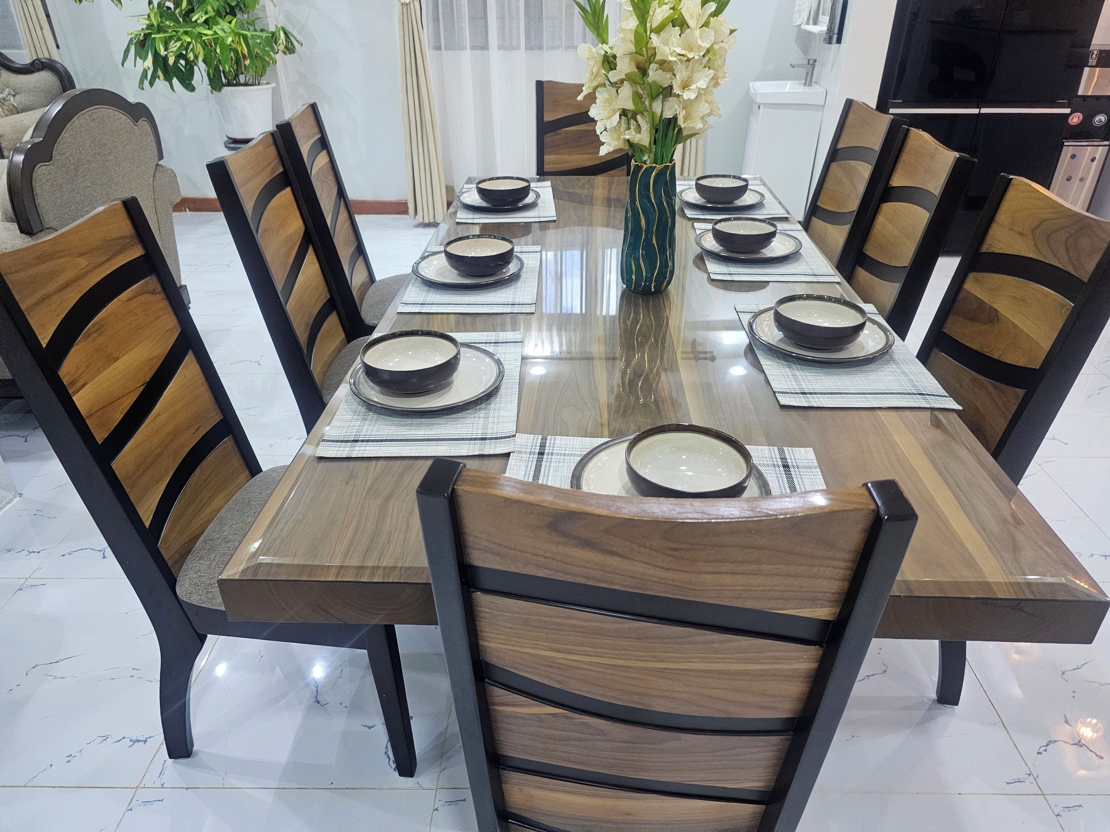 Une table à manger dressée avec des assiettes, des bols et un vase rempli de fleurs.