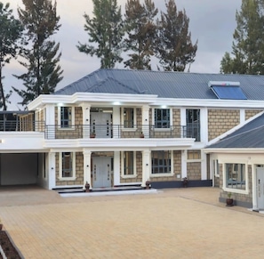 A two-story building with a flat roof, a covered entrance, and a paved driveway. - Serene 4-bedroom resort in welcoming Eldoret for your getaway (Eldoret)