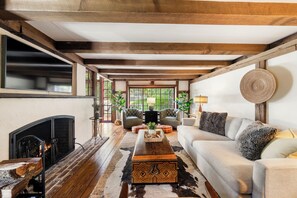 Una sala de estar acogedora con chimenea, vigas de madera, un sofá y una mesa de centro.