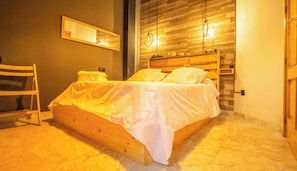 A bedroom with a wooden bed, a nightstand, a chair, a mirror, and a wall-mounted light fixture. - A charming apartment right in the heart of Granada. (Granada)