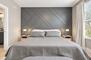 A modern bedroom with a large bed, two bedside tables, and a window with curtains. - Westfield Landing | Walkable • Carmel • Designer (Westfield)