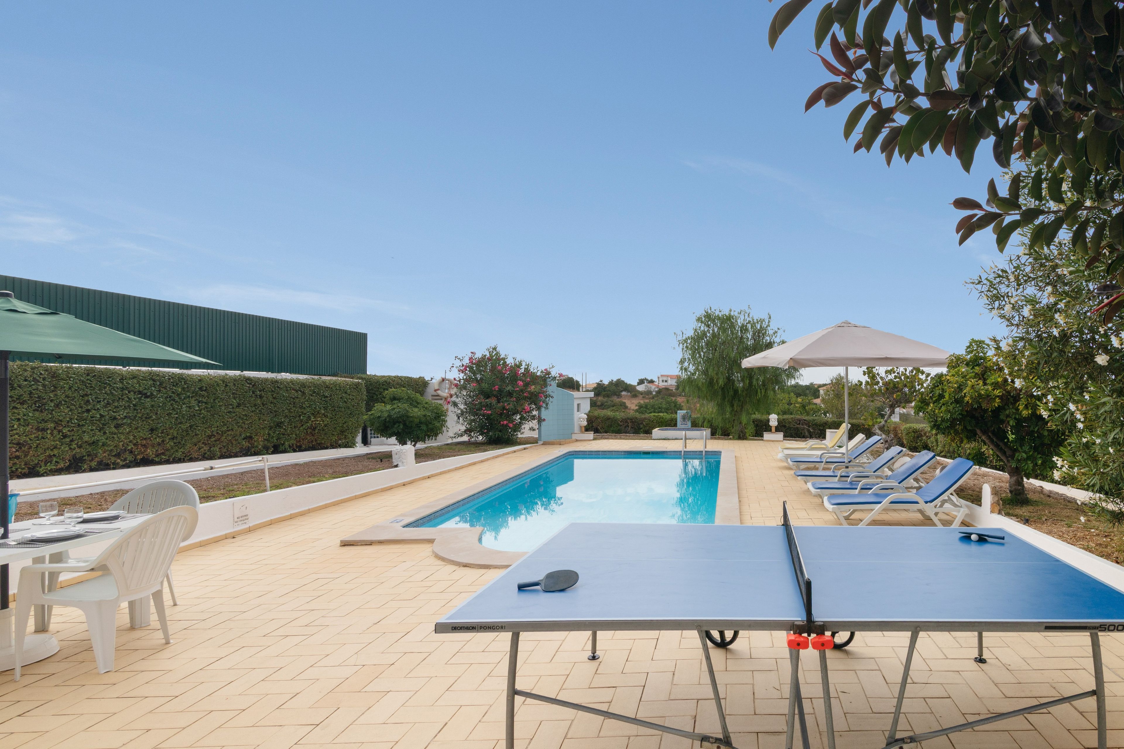 Ein Schwimmbad mit Liegestühlen und einem Tischtennis-Tisch.
