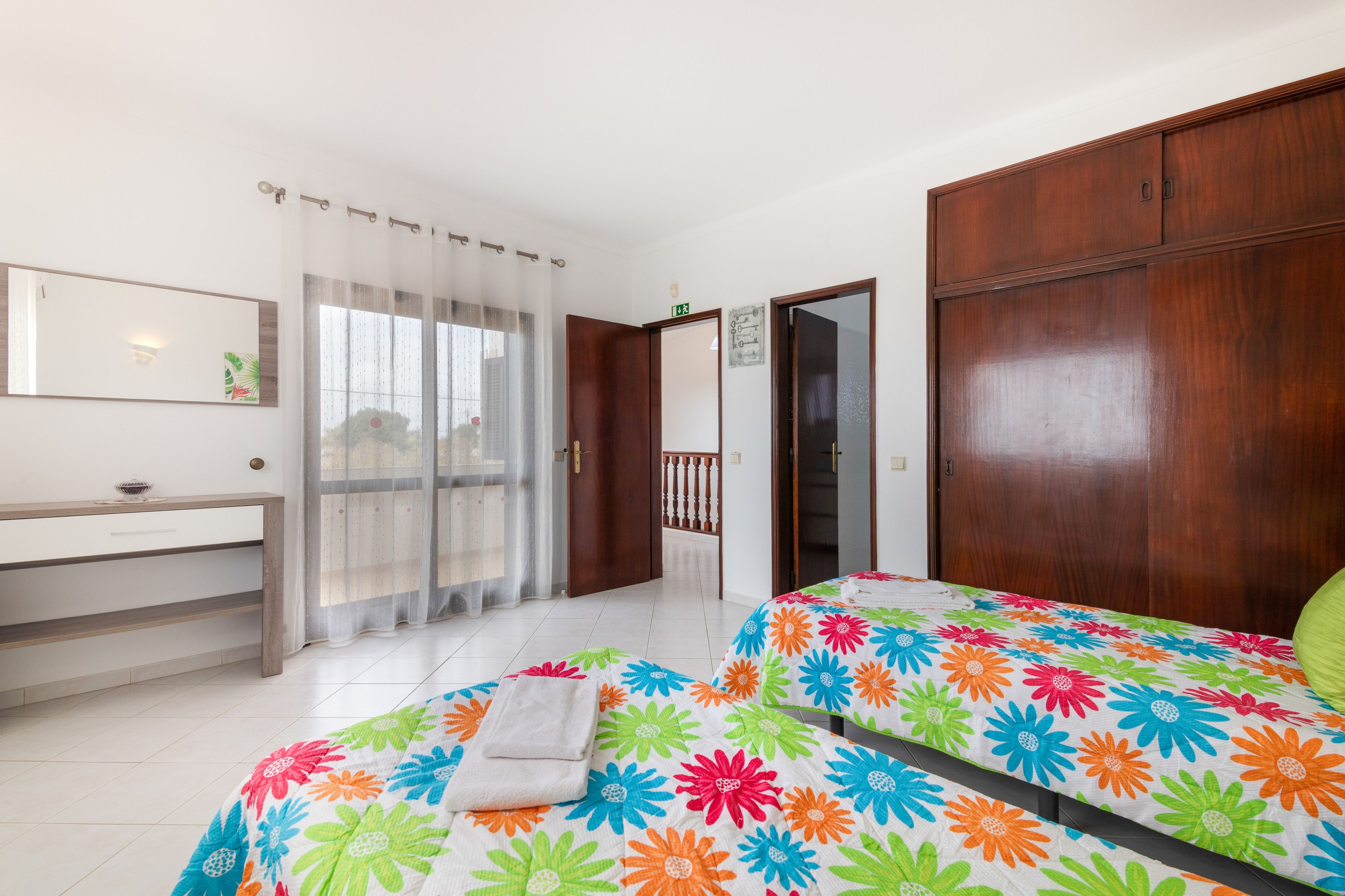 Une chambre à coucher avec un lit, une armoire en bois, une salle de bain avec un miroir et un rideau de douche.