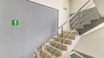 A staircase with a metal handrail and a door marked with a green exit sign.