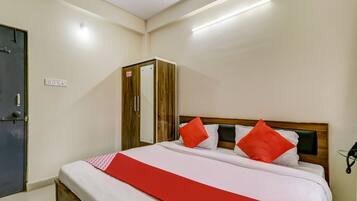 A hotel room with a bed, a wardrobe, and a door.