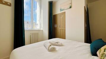 Une chambre à coucher avec un lit, une fenêtre avec des rideaux, un radiateur et une armoire en bois.