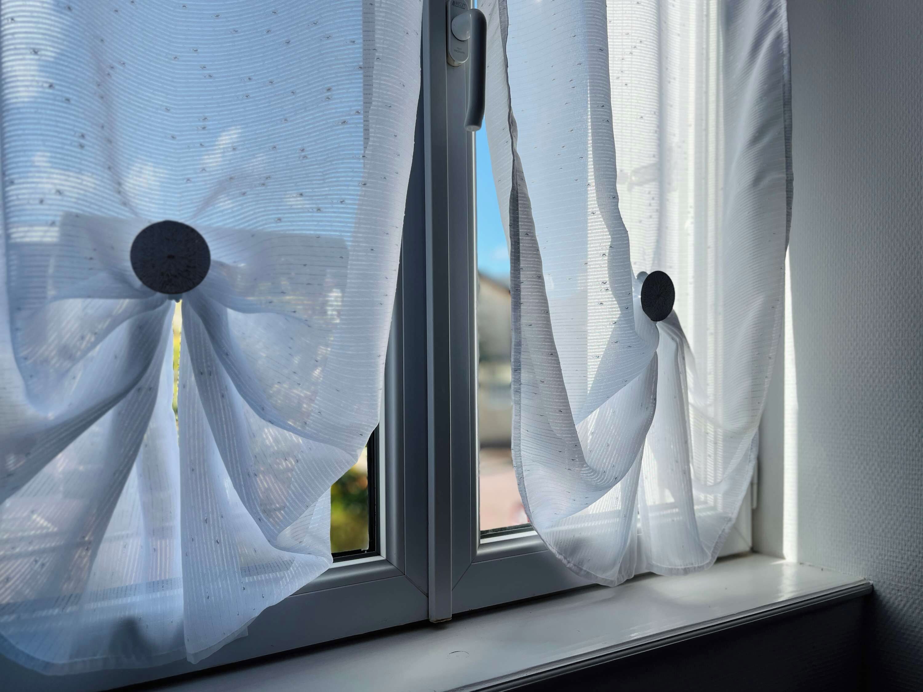 A window with sheer white curtains and a visible door handle.